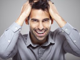 Smiling man with dark hair holding his head, expressing happiness and relief after emotional and physical transformation through RN-led root